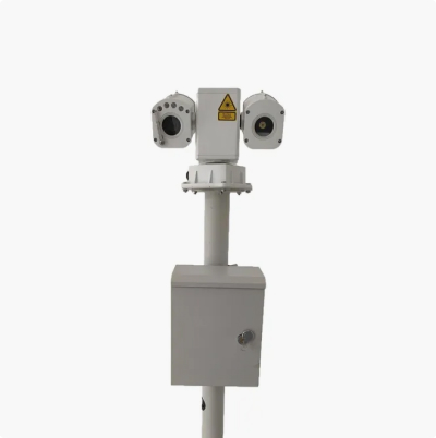 Industrial monitoring device mounted on a pole with dual sensor units, warning label, and weatherproof control enclosure.