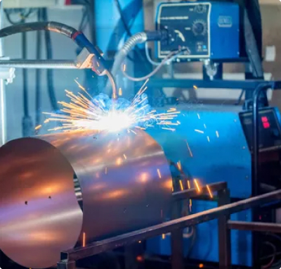 Automated welding process on an aluminum component with visible sparks inside an industrial manufacturing facility.