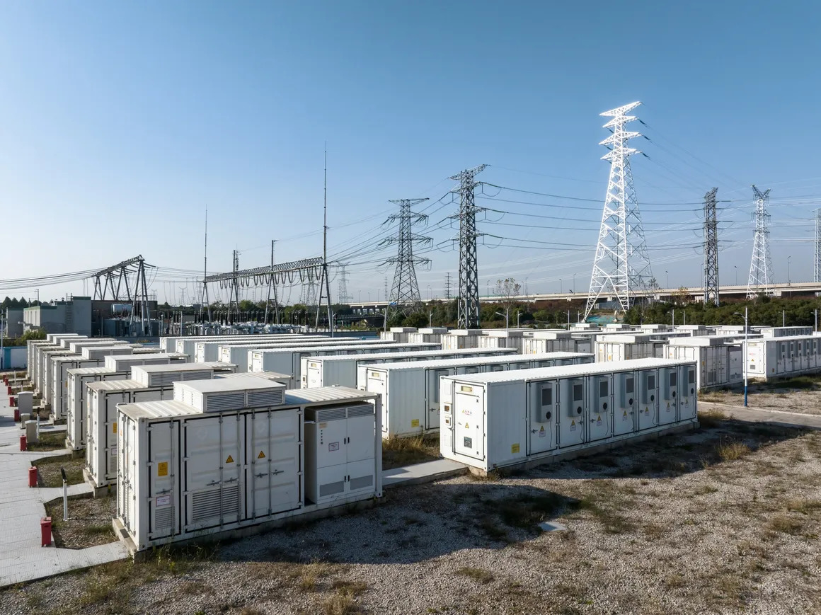High-voltage power transformer installed at an electrical substation with bushings, cooling radiators, and overhead transmission connections.