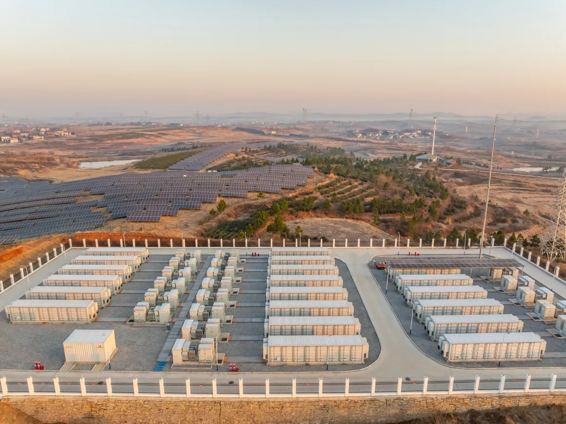 Large-scale battery energy storage facility with rows of containerized battery units installed near a solar power plant in an open landscape.
